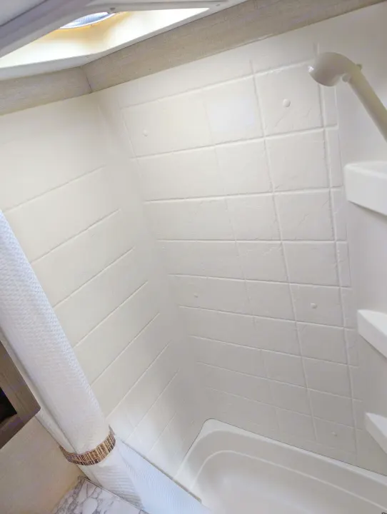 Inside an rv rental, a compact, clean shower stall with molded tile-look walls, a showerhead, and ceiling vent for travel comfort.. Keystone RV Bullet Crossfire 2018
