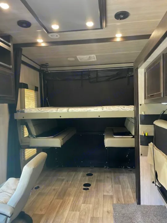 This RV rental's versatile rear garage features a convertible bunk bed and seating, ideal for gear or extra sleeping space.. Genesis Supreme Rv RAGE'N 2815T Fifth Wheel 2023