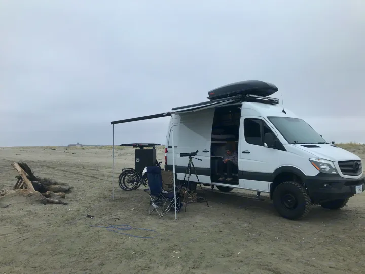 Enjoying a beach day in a Mercedes Sprinter rv rental, complete with an e-bike & spotting scope. Perfect for outdoor adventures!. Mercedes Benz Sprinter 2018