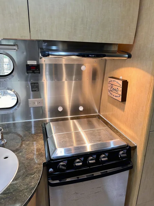 Compact RV kitchen with stainless steel appliances and wood cabinets, perfect for your rv rental getaway.. Airstream Flying Cloud 2016