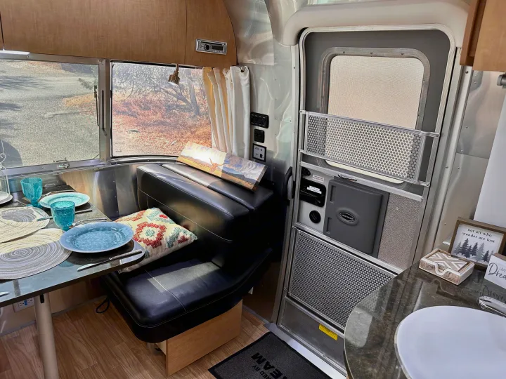 Inside a modern Airstream RV rental, showing the cozy dinette with place settings, control panel, and screen door.. Airstream Flying Cloud 2016