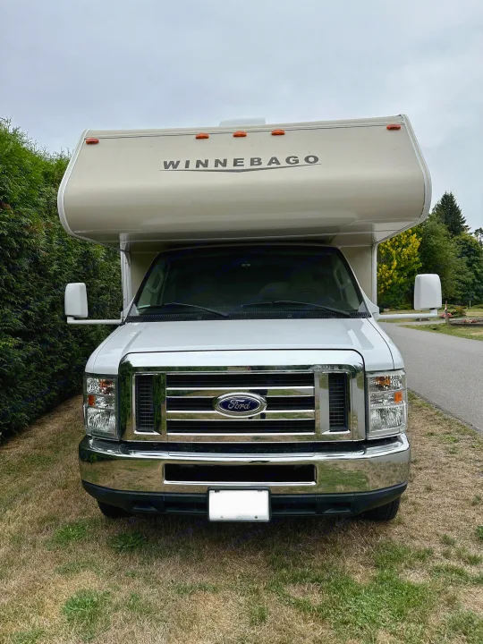 Front view of a white Winnebago RV rental, a Ford Class C motorhome, parked on a grassy area.. Winnebago Minnie Winnie 2014