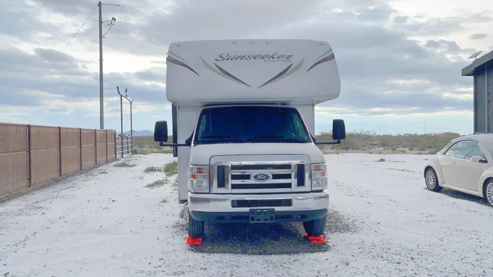 Snow-dusted Sunseeker RV rental with orange leveling blocks, ready for winter travel in a desert setting.. Forest River Sunseeker 2017