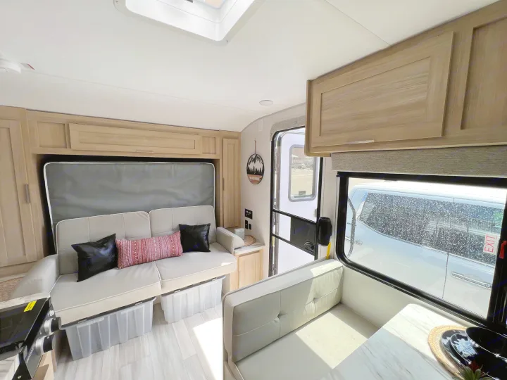Bright, functional **rv rental** interior featuring a versatile sofa bed, under-couch storage bins, and a dining area. Ready for your trip!. Forest River Salem FSX 2023