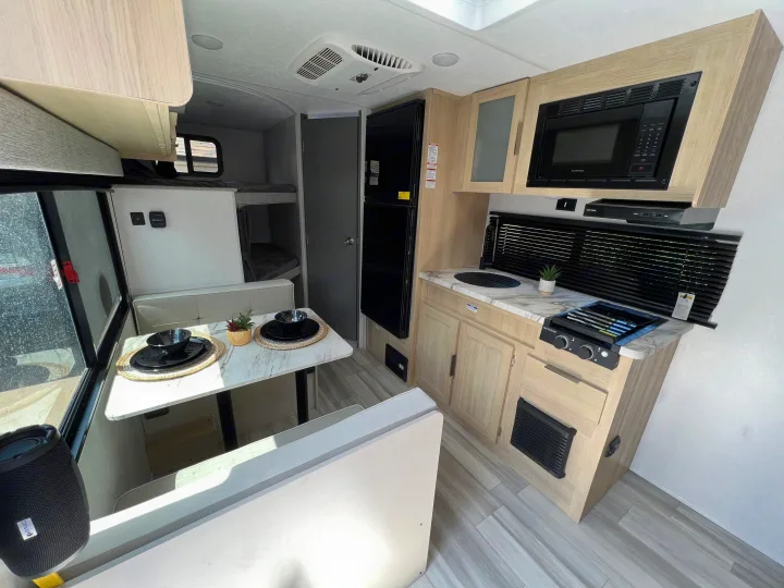 Modern RV rental interior featuring a bright dinette, compact kitchen, and cozy bunk beds. Ready for travel!. Forest River Salem FSX 2023