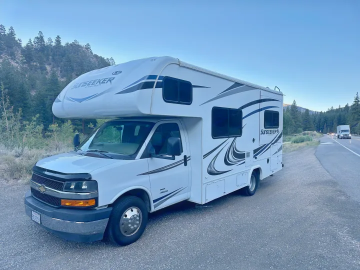 White Sunseeker Class C rv rental parked roadside amidst mountains and forest.. Forest River Sunseeker LE 2020
