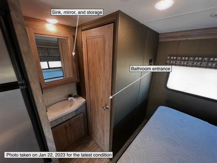 RV rental interior showing sink, mirror, bathroom entrance, and part of a bed. Functional space for your trip.. Forest River Sunseeker LE 2020