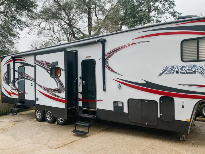 White Vengeance travel trailer RV rental with sleek black/red graphics and extended steps.. Forest River Vengeance 2015