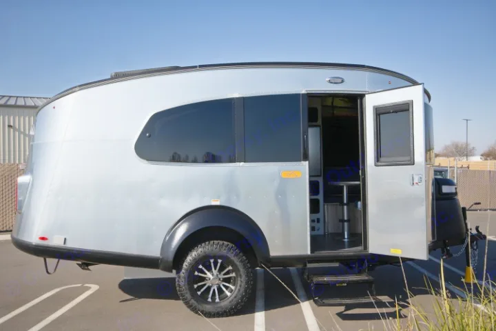 Modern silver travel trailer with open door, showing interior. This sleek camper is perfect for an RV rental adventure.. Airstream Base Camp 2022