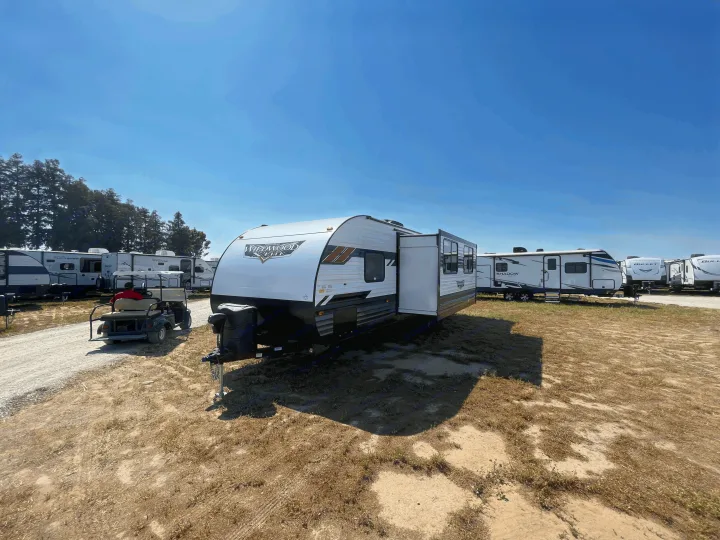 Sunny outdoor RV rental lot displays rows of white travel trailers, including a Forest River Wildwood Elite, on a clear day.. Forest River Wildwood X-Lite 2022
