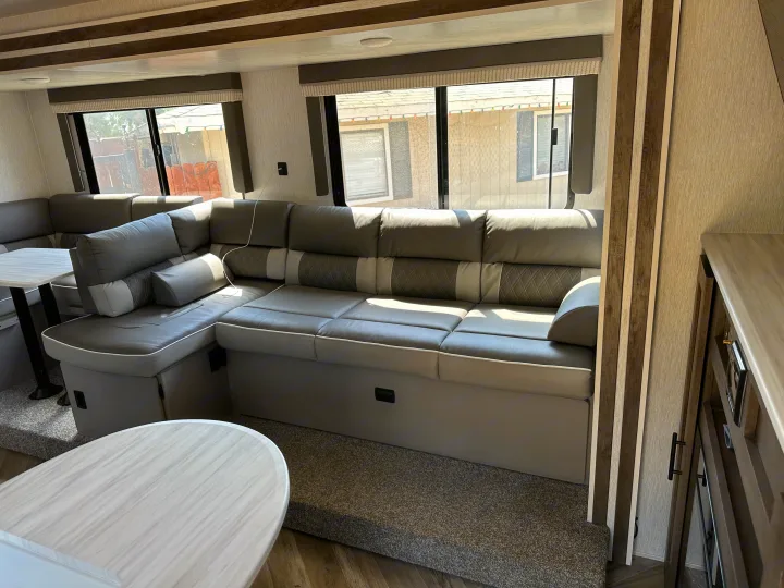 Comfortable RV rental interior: L-shaped sofa, dining table, and large windows for a bright stay.. Forest River Wildwood X-Lite 2022
