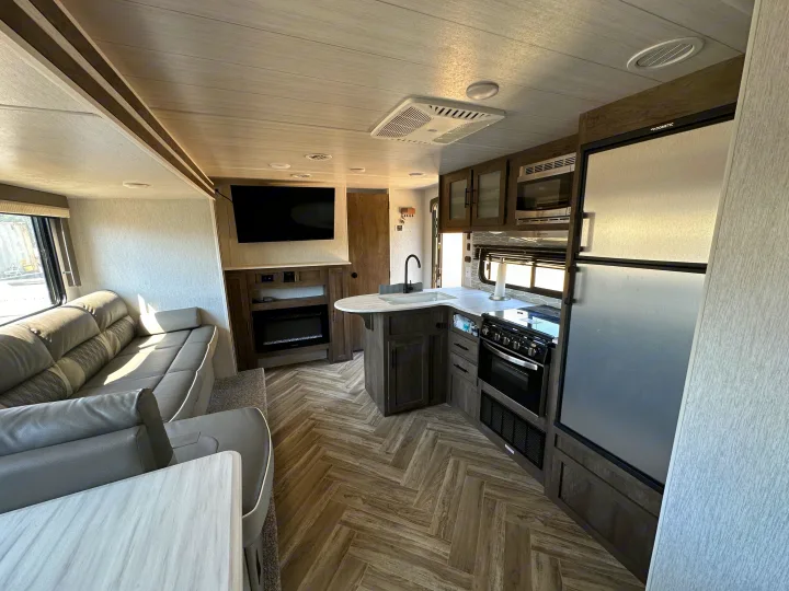Spacious RV rental interior featuring a modern kitchen, comfortable living area with TV, and cozy electric fireplace.. Forest River Wildwood X-Lite 2022