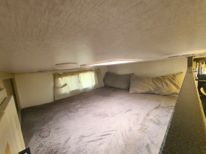 This RV rental offers a cozy, elevated sleeping space with a soft blanket and plush pillows for comfortable travel.. Palomino Columbus 2022