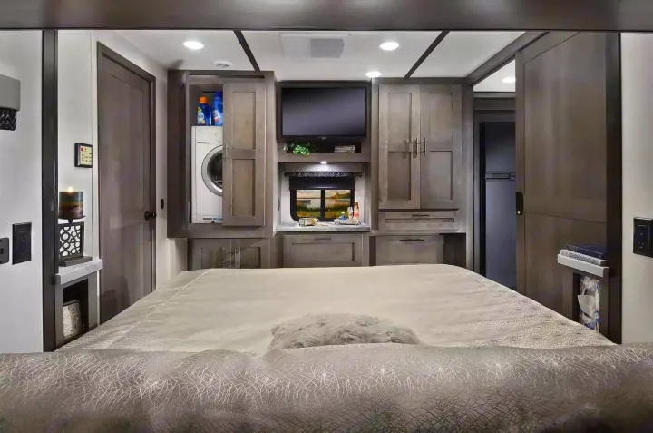 Spacious RV rental bedroom with integrated washer/dryer, TV, and ample storage, perfect for comfortable travel.. Forest River 34DS 2022