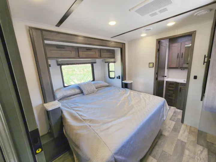 Bright RV rental bedroom featuring a large bed, windows with a view, and smart storage solutions.. Forest River 34DS 2022