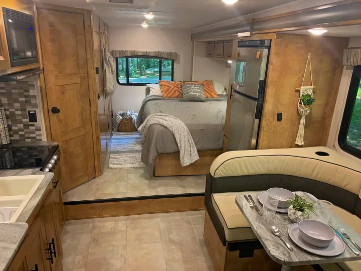 Cozy rv rental interior featuring a compact kitchen, comfortable dining booth, and a well-appointed bedroom area.. Forest River Coachmen Leprechaun 2020