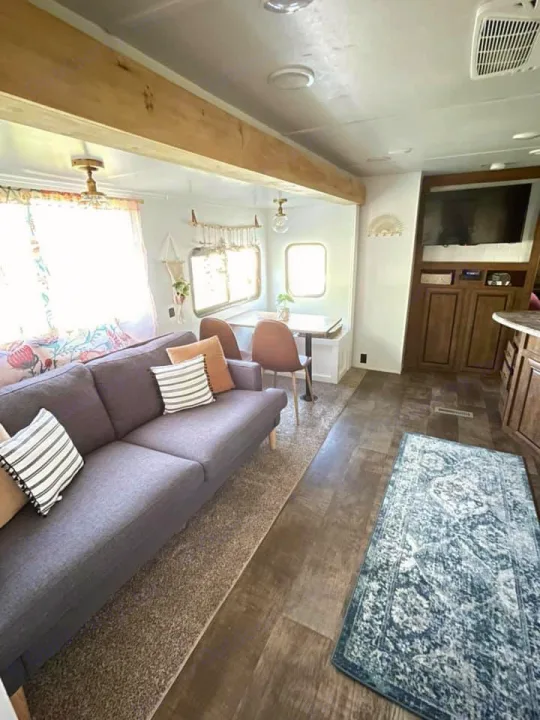 Inside a cozy RV rental: living room with sofa, dining area, and part of the kitchen. Features wood flooring & modern decor.. Crossroads RV Zinger 2017