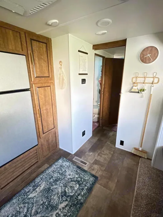 Inside a modern RV rental: bright walls, wood-look floors, built-in cabinets, and a refrigerator offer comfort.. Crossroads RV Zinger 2017