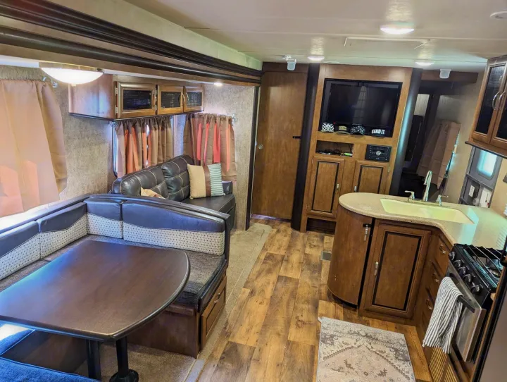 Spacious RV rental interior with U-shaped dinette, kitchen featuring sink & stove, and TV entertainment area. Ready for adventures!. Forest River Salem 2017