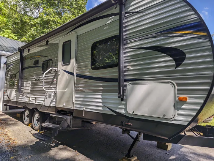 RV rental: Parked gray Salem travel trailer, side view showing rolled-up awning and leveling blocks.. Forest River Salem 2017