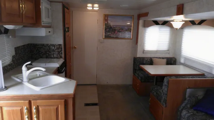 Inside this RV rental: a well-equipped kitchen (sink, microwave, stove) & cozy dining booth for comfortable travel.. Other Other 2002