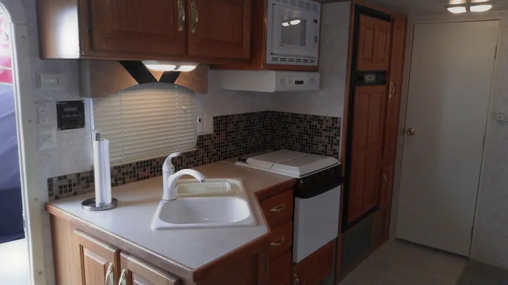 Explore this RV rental's well-equipped kitchen: wood cabinets, sink, microwave, range, & refrigerator.. Other Other 2002