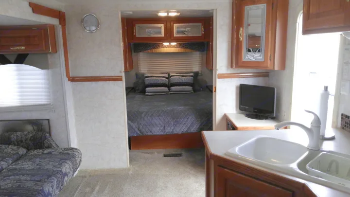Step inside this RV rental, featuring a functional kitchen area, cozy bedroom, and comfortable living space.. Other Other 2002