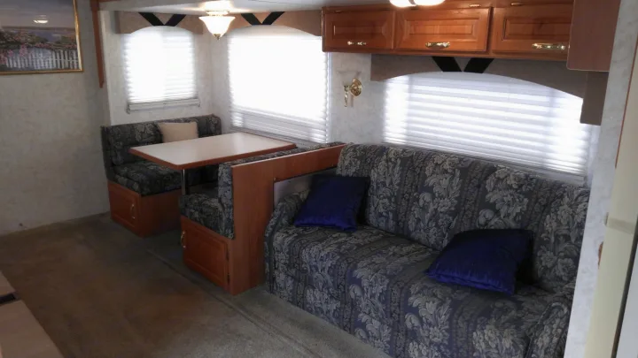 RV rental interior featuring a spacious dinette, comfy sofa, and overhead cabinets for an ideal travel living space.. Other Other 2002