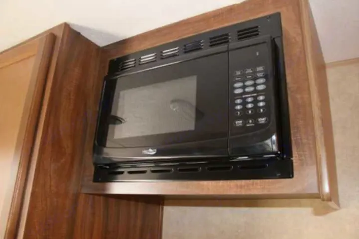 RV rental interior: A built-in black microwave blends with the warm wood cabinetry of this functional kitchen.. Clipper Clipper Trailer 2016