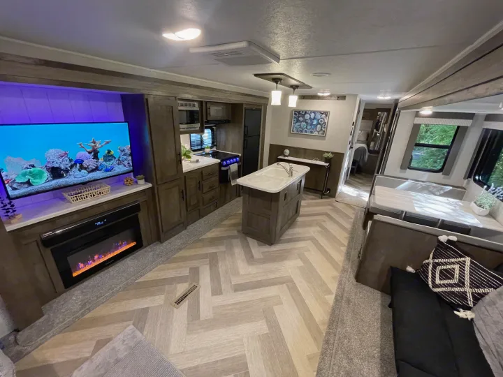 Spacious RV rental interior featuring a modern kitchen with island, living area with TV and fireplace, and dining booth.. Forest River Salem 2021
