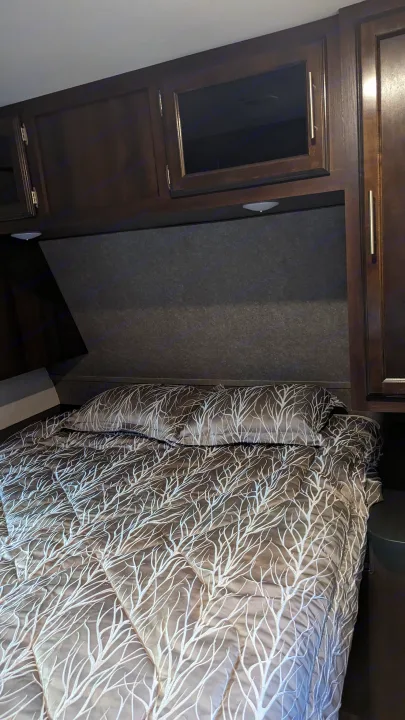Cozy RV rental bedroom with a comfy bed, unique tree-patterned comforter, and convenient overhead storage cabinets.. Jayco Jay Flight 2019