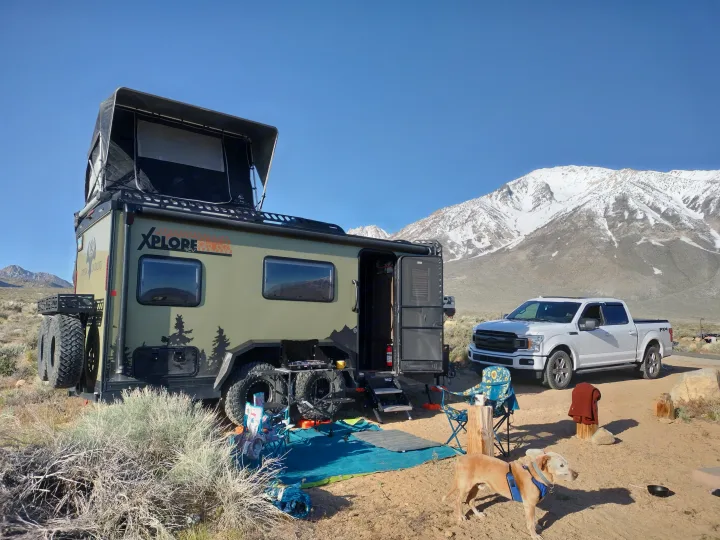 Our XPLORE rv rental setup with a white F-150 truck, dog, and camp gear, surrounded by majestic snow-capped mountains.. Xplorer X22 2022