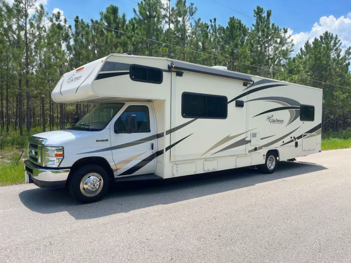 Spacious Coachmen Freelander RV rental parked on asphalt with pine trees in the background, ready for your next adventure.. Forest River Coachmen Freelander 2018