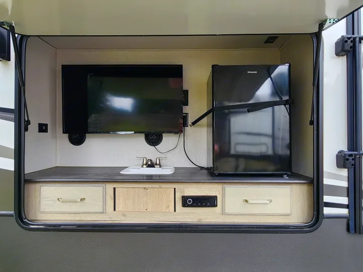 This RV rental features a full outdoor kitchen: TV, sink, mini-fridge, media player, and storage. Ideal for camping entertainment.. Keystone Avalanche 2021