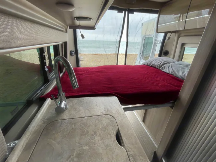 Enjoy this RV rental! Inside, a comfy bed and sink face large windows with a stunning beach and ocean view. Relaxing travel.. Thor Scope 2023