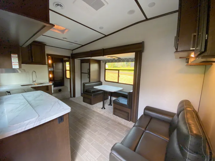Spacious RV rental interior with a modern kitchen, dinette booth, and leather sofa, offering comfortable travel living.. Atlas Atlas Fifth Wheel 2020