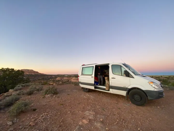 Adventure awaits! This Sprinter **rv rental**, with a person and dog, enjoys a beautiful desert sunset.. Mercedes-Benz Sprinter 2012