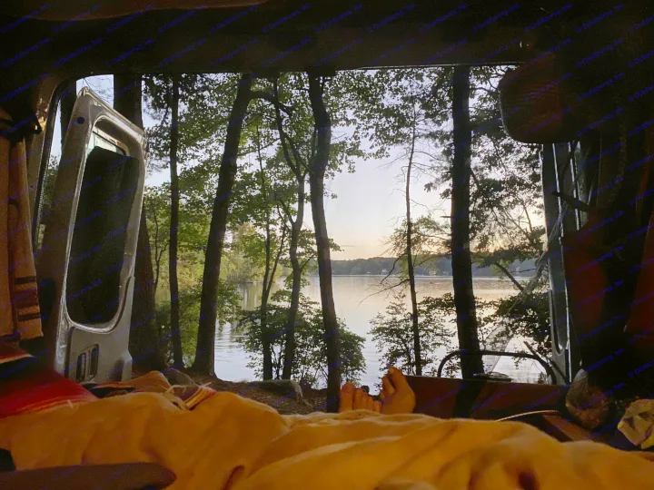 Cozy view from an RV rental, feet up, overlooking a tranquil lake through silhouetted trees at sunset.. Mercedes-Benz Sprinter 2012
