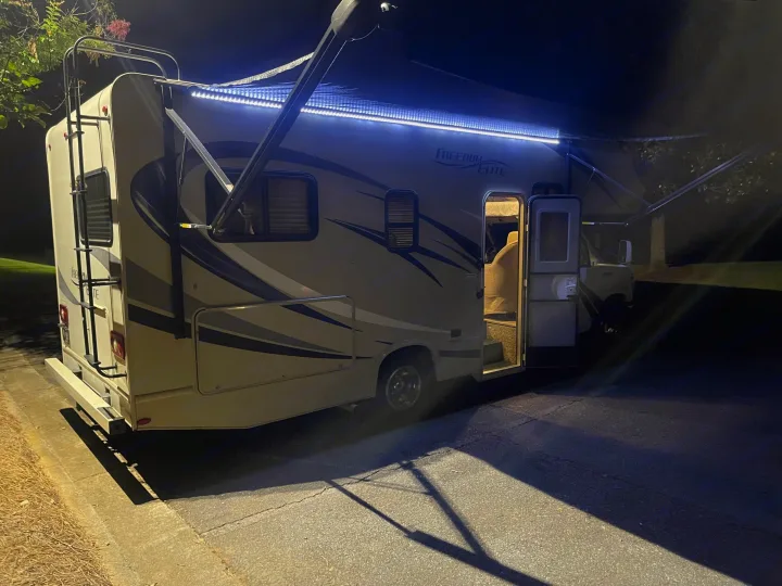 Brightly lit RV rental at night with open door & awning, ready for adventure.. Thor Freedom Elite 2018