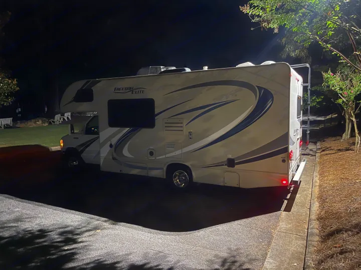 A white Freedom Elite RV is parked at night under artificial light, ready for your next rv rental trip.. Thor Freedom Elite 2018