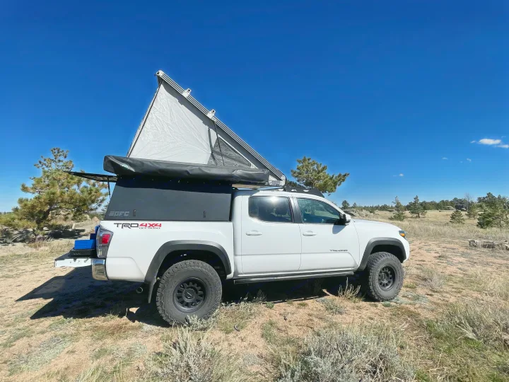 White Tacoma pickup with GFC rooftop tent & awning deployed. A versatile RV rental alternative for off-road camping.. 2023