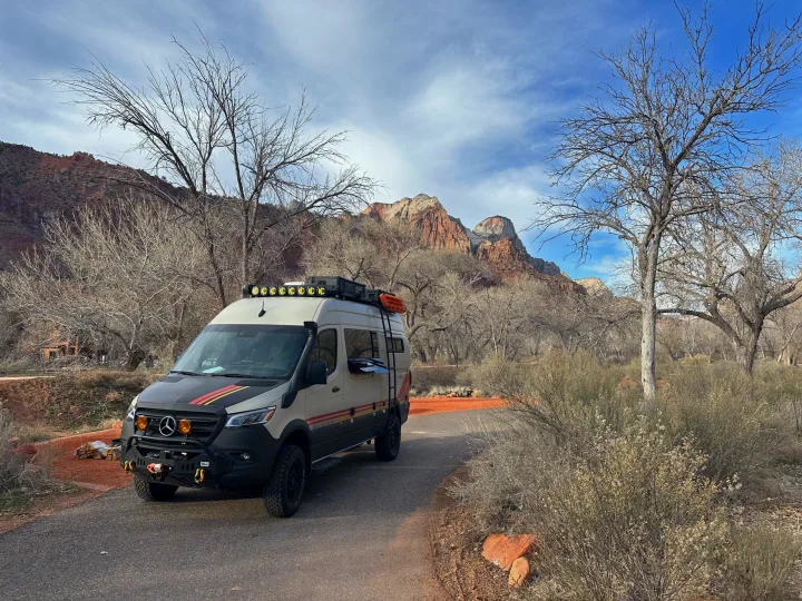 Adventure-ready Storyteller Overland RV rental van parked in scenic Zion National Park, surrounded by red rock mountains and bare trees.. Storyteller Overland Storyteller Overland Class B 2022