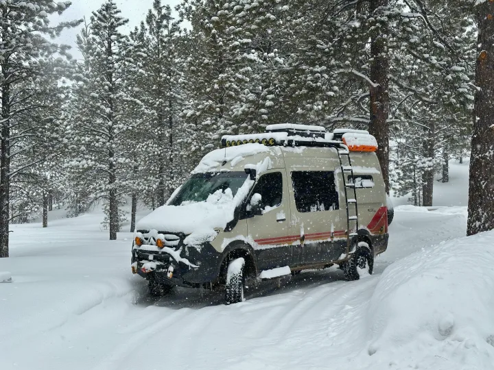 Snowy adventure with an RV rental: This rugged camper van is parked in deep winter snow surrounded by pine trees.. Storyteller Overland Storyteller Overland Class B 2022