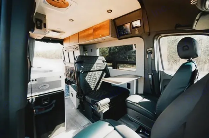 RV rental interior: A comfortable space with swiveling passenger seat, work table, overhead storage, and ceiling fan.. Storyteller Overland Storyteller Overland Class B 2022