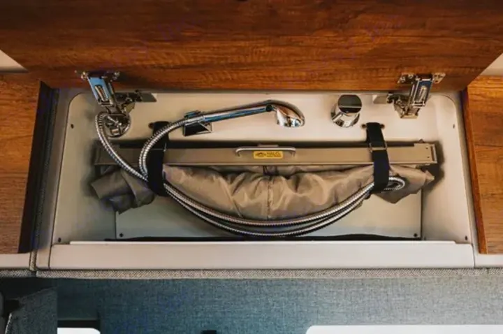 This RV rental features a clever pull-out shower head and collapsible sink stored in an overhead cabinet, optimizing compact van life space.. Storyteller Overland Storyteller Overland Class B 2022