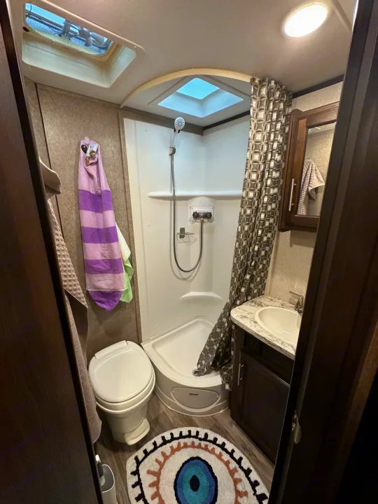 Compact RV rental bathroom, featuring a corner shower, toilet, and small sink vanity.. Jayco Jay Feather 2018