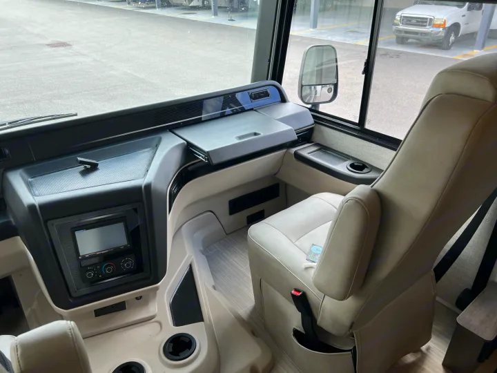 RV rental cockpit view, showcasing a modern dashboard, touchscreen, and comfortable captain's chairs.. Entegra Coach Vision XL 2023