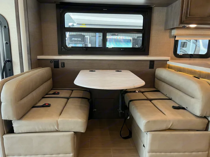 This comfortable RV rental features a well-lit dinette with two cushioned benches, a table, and seatbelts for safe travel.. Entegra Coach Vision XL 2023