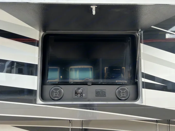 This RV rental features an outdoor entertainment system with a TV, speakers, and power outlet, ready for adventure.. Entegra Coach Vision XL 2023