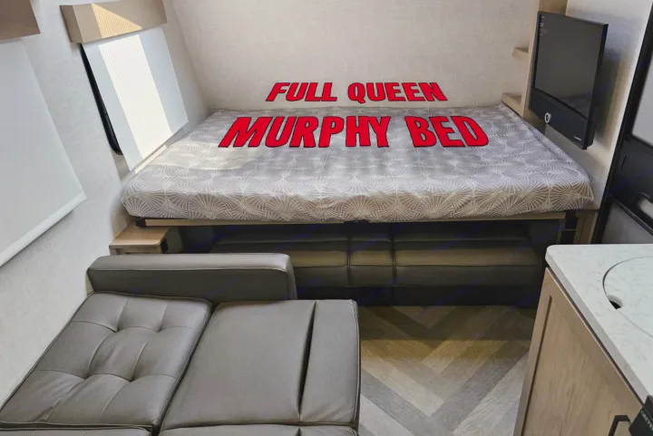 RV rental interior featuring a full queen Murphy bed folded down over a cozy sofa, maximizing space for travel.. Ember Overland 2022